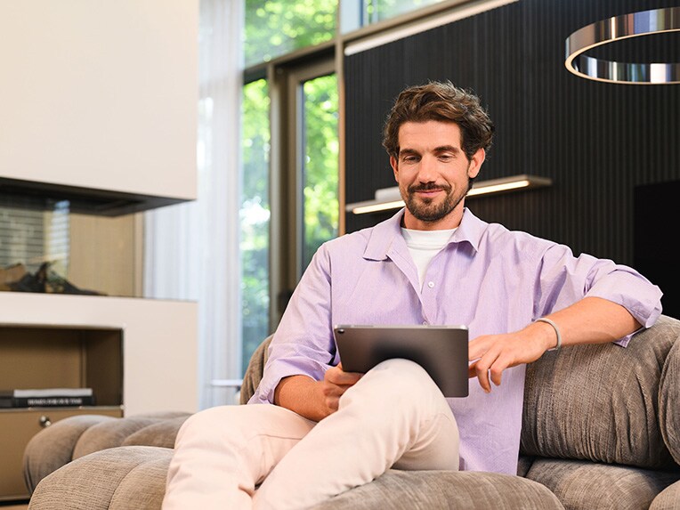 Financiamiento y Arrendamiento para tu van Mercedes-Benz Una persona sentada en un sofa viendo un dispositivo móbil